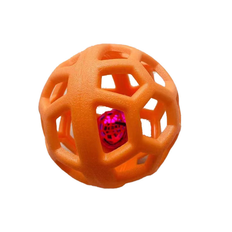 Orange geometric dog chew ball with a glossy red inner bell on a light grey surface.