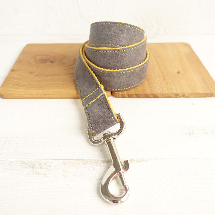 Gray dog leash with yellow stitching on a wooden board