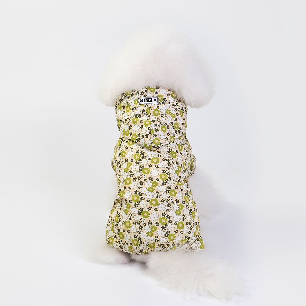 White fluffy dog wearing a yellow floral hooded jacket, sitting with its back facing the camera