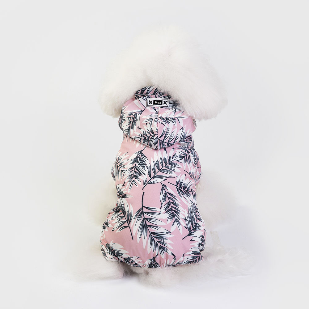 Small white fluffy dog wearing a pink hooded jacket with a black leaf pattern, facing away from the camera