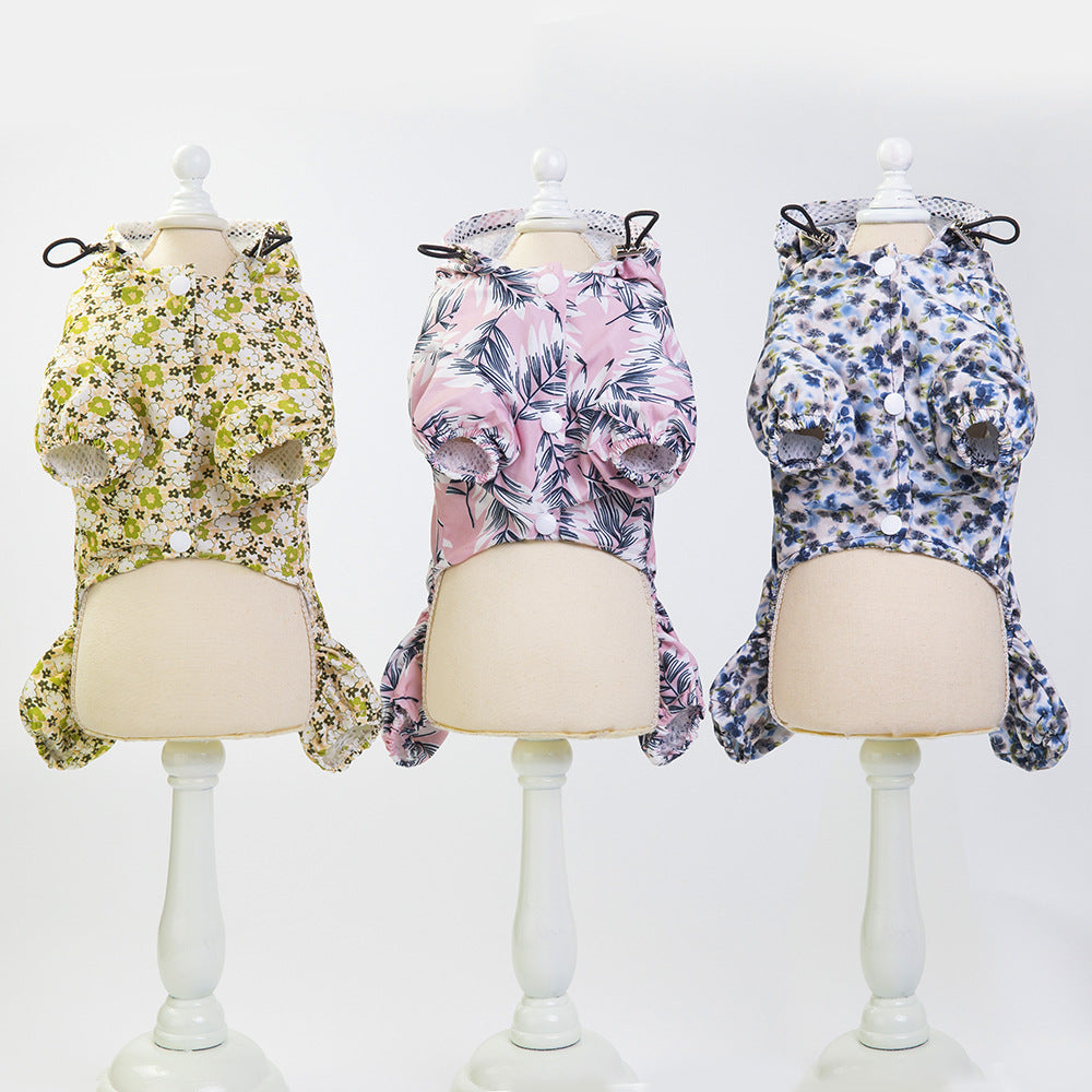 Three dog raincoats with floral patterns displayed on mannequins, each with a hood and button‑front design.