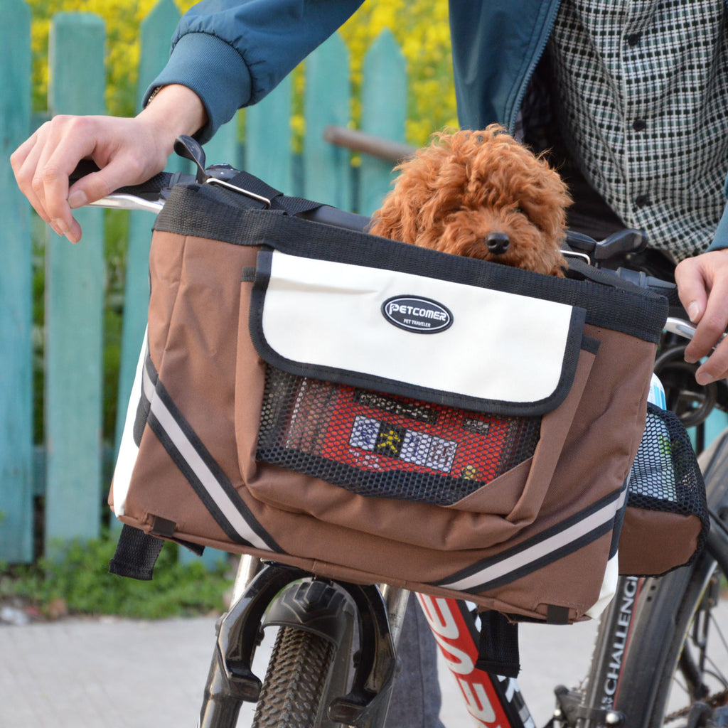 Brown bicycle pet carrier with a dog inside, attached to a bike with a blurred background.