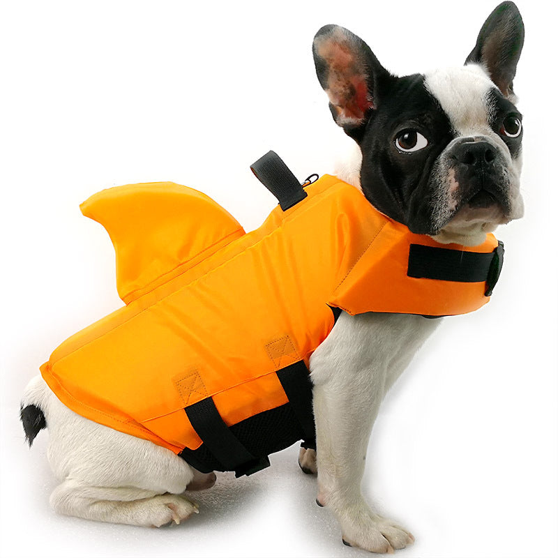 Side view of dog sitting with life vest with shark design in orange