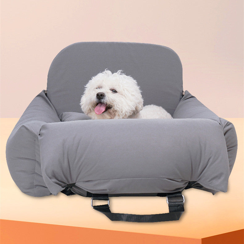 Dog sitting in a gray pet car seat on a peach background