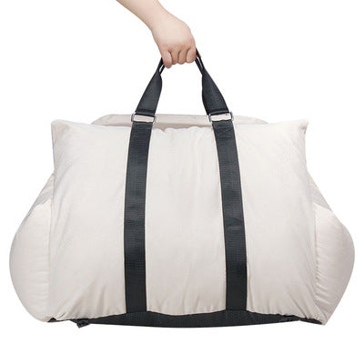 White duffel bag with black straps held by a hand on a white background