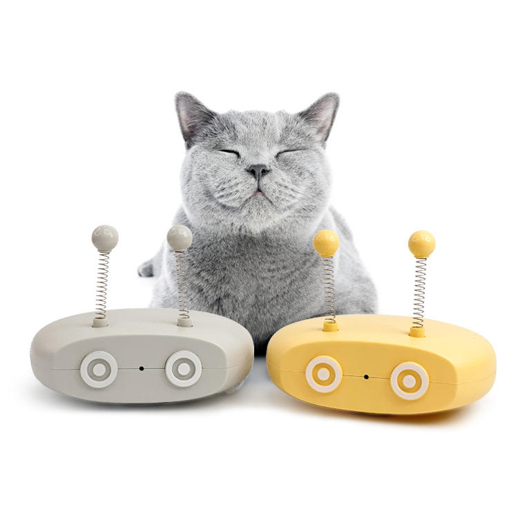 Gray cat sitting between two colorful cat toys on a white background