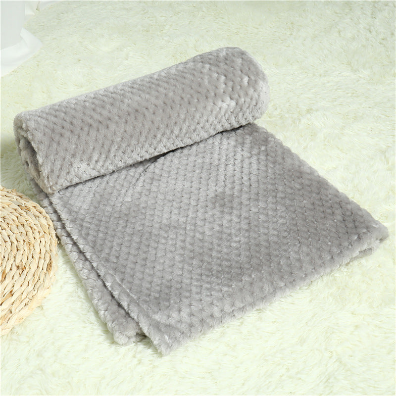 Folded gray blanket on a light green surface