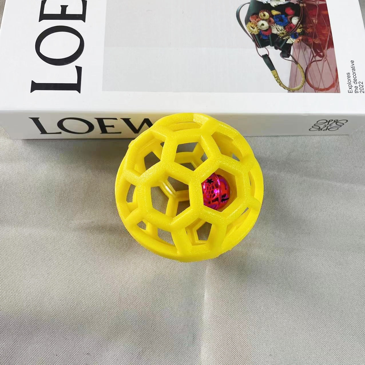 Yellow textured ball with a red bell center on a gray surface