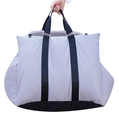 White travel bag with black straps held by a hand on a white background