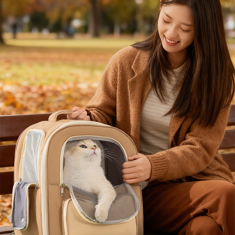 Woman holding a beige pet carrier with a cat inside, sitting on a park bench.