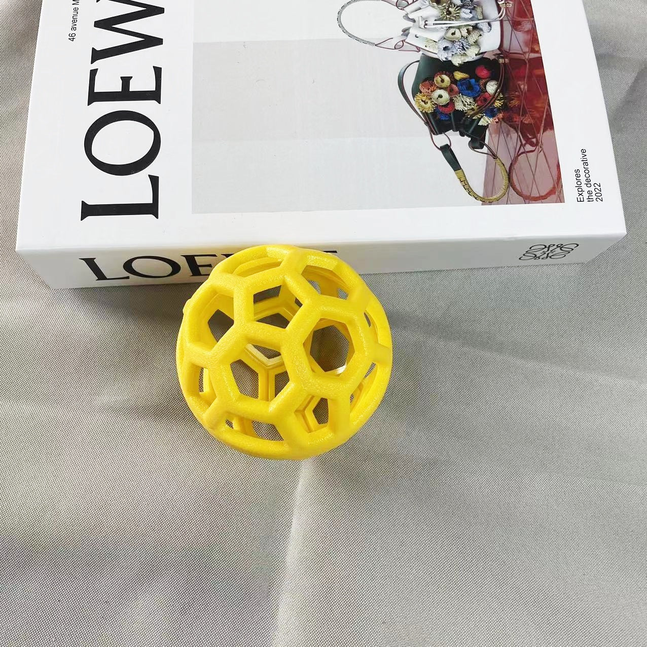 Yellow geometric ball on a gray surface with a white box.
