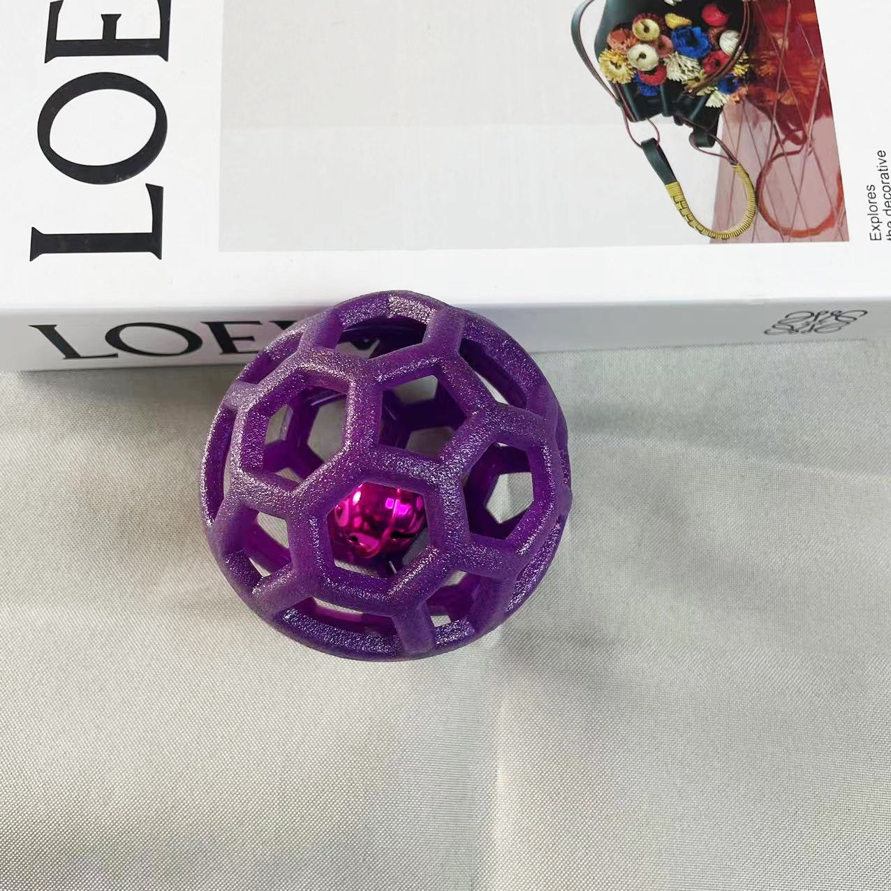 Purple hollow geometric dog chew ball with pentagon and hexagon openings shown on a plain surface.