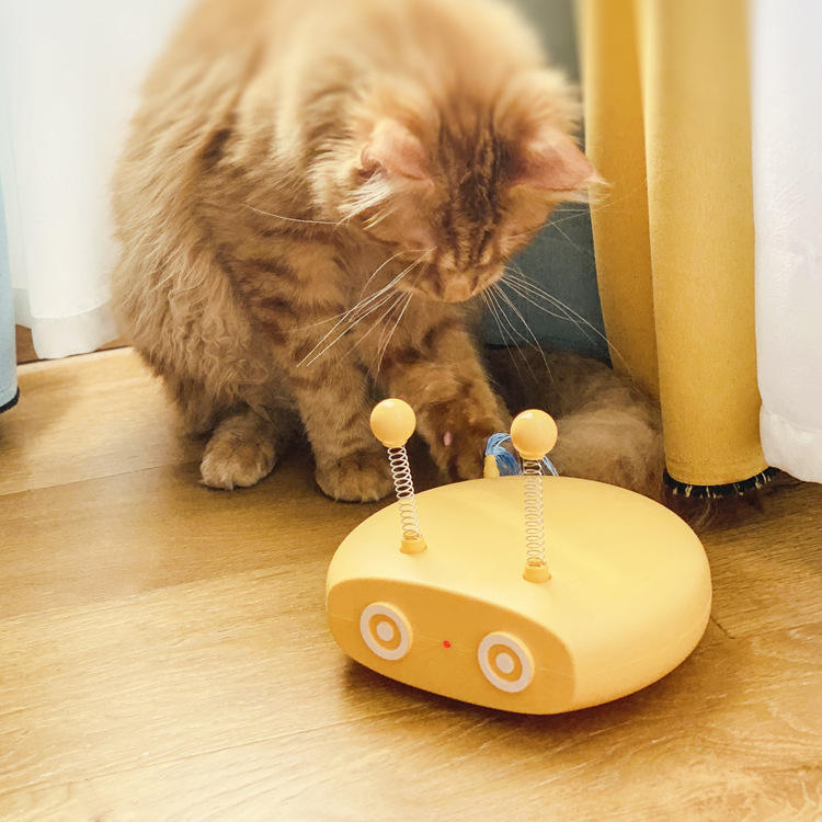 Cat playing with a yellow robot-shaped toy on a wooden floor.