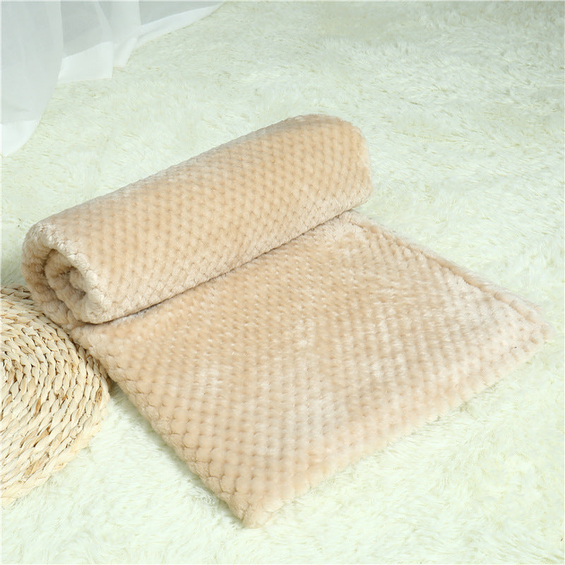 Beige textured blanket on a light green surface with a woven basket.