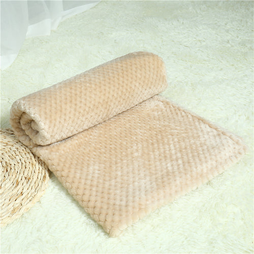 Beige textured blanket on a light green surface with a woven basket.