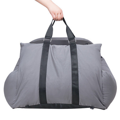 Gray duffel bag with black straps held by a hand on a white background