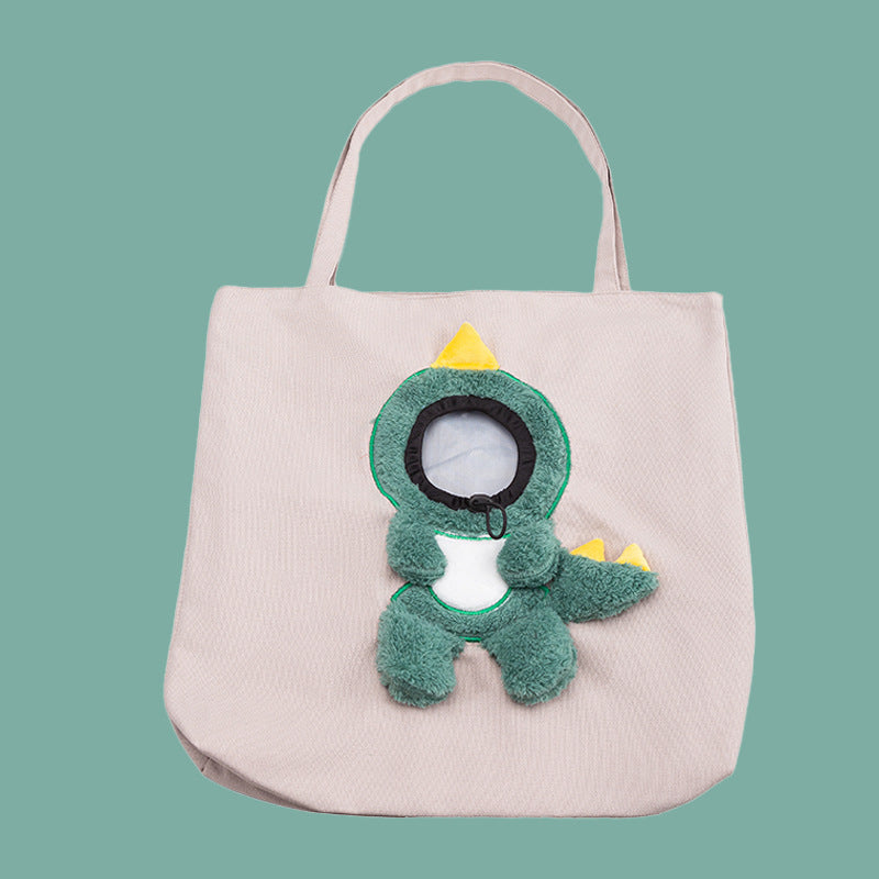 Beige tote bag with a green dinosaur plush toy on a teal background